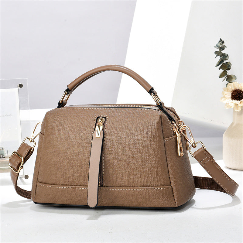 Oleg bag - Brown handbag with gold accents on a white surface