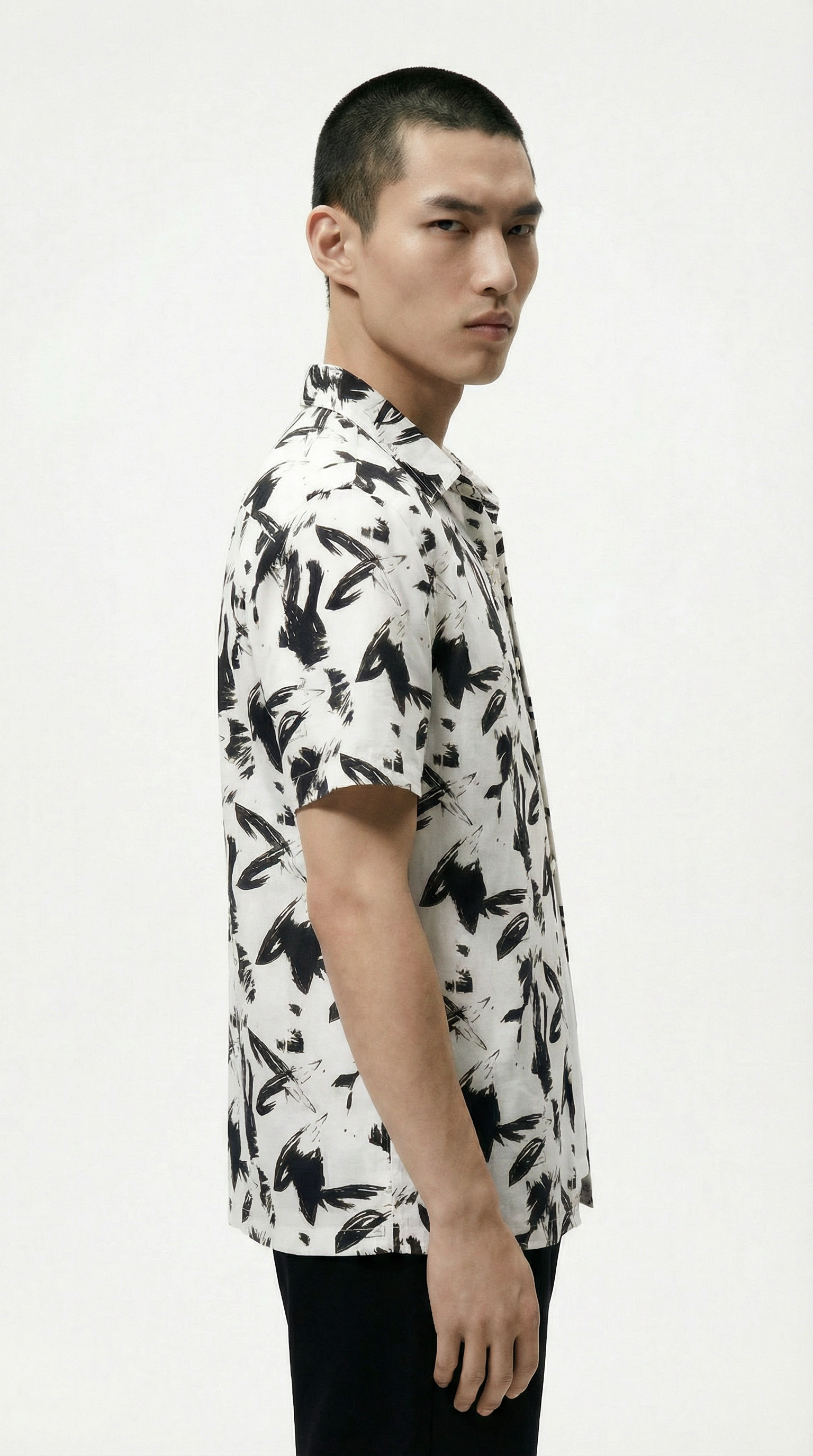 Man wearing a white shirt with black floral pattern on a white background