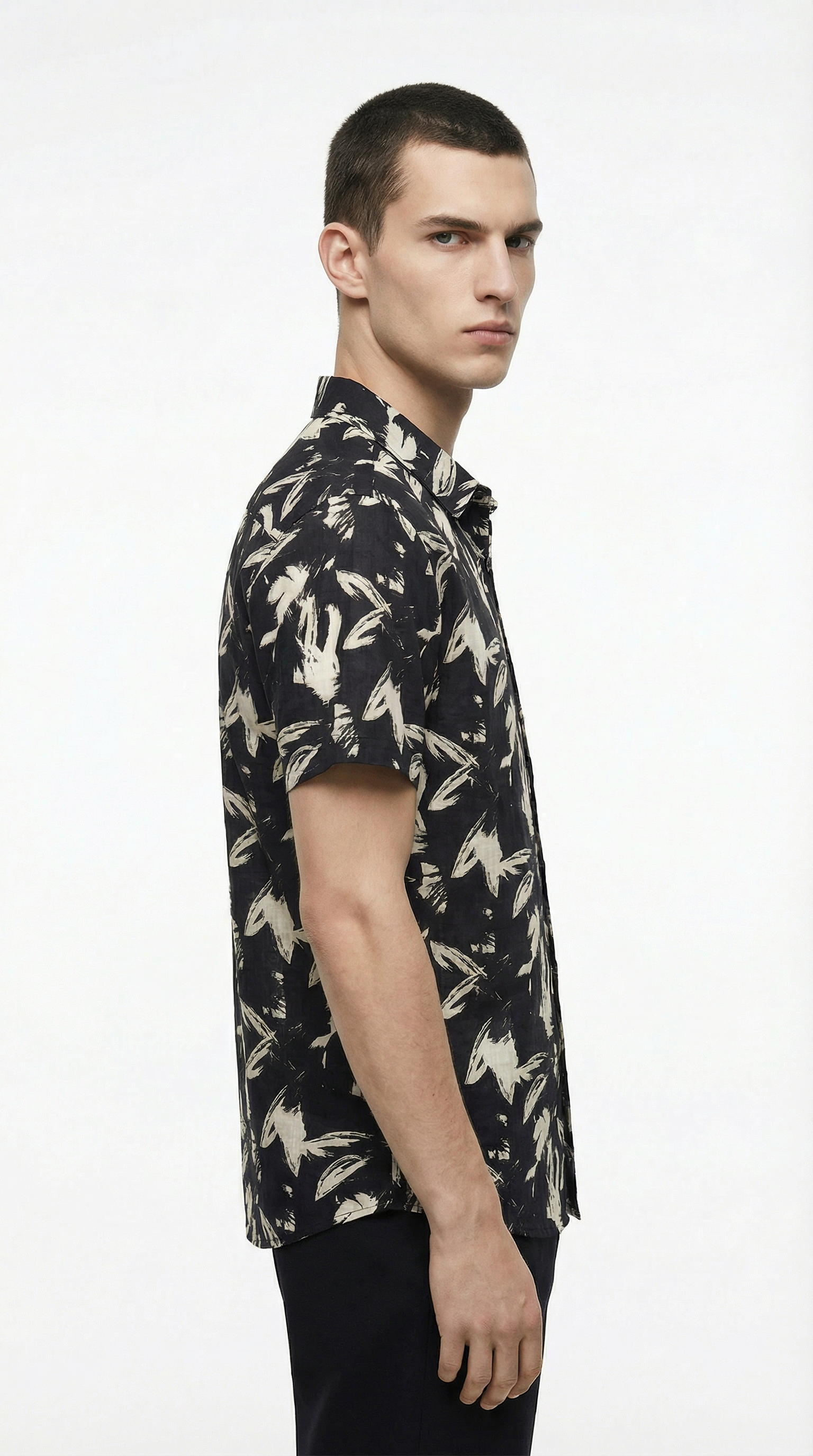 Man wearing a black floral patterned shirt on a white background