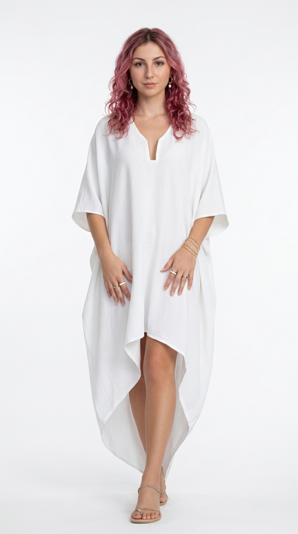 A woman with pink hair wearing a white high-low kaftan dress, standing against a plain white studio background, from Meleche Fashion or Meléche (short as (Mé)) and shoot taken by Meléche studio photography NYC-USA