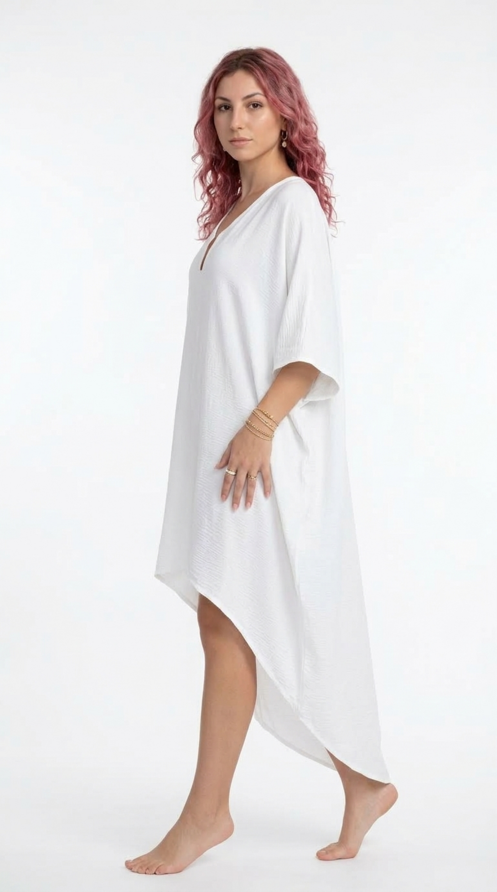 A woman with pink hair wearing a white, loose-fitting kaftan-style cover-up dress, standing against a plain white studio background, from Meleche Fashion or Meléche (short as (Mé)) and shoot taken by Meléche studio photography NYC-USA