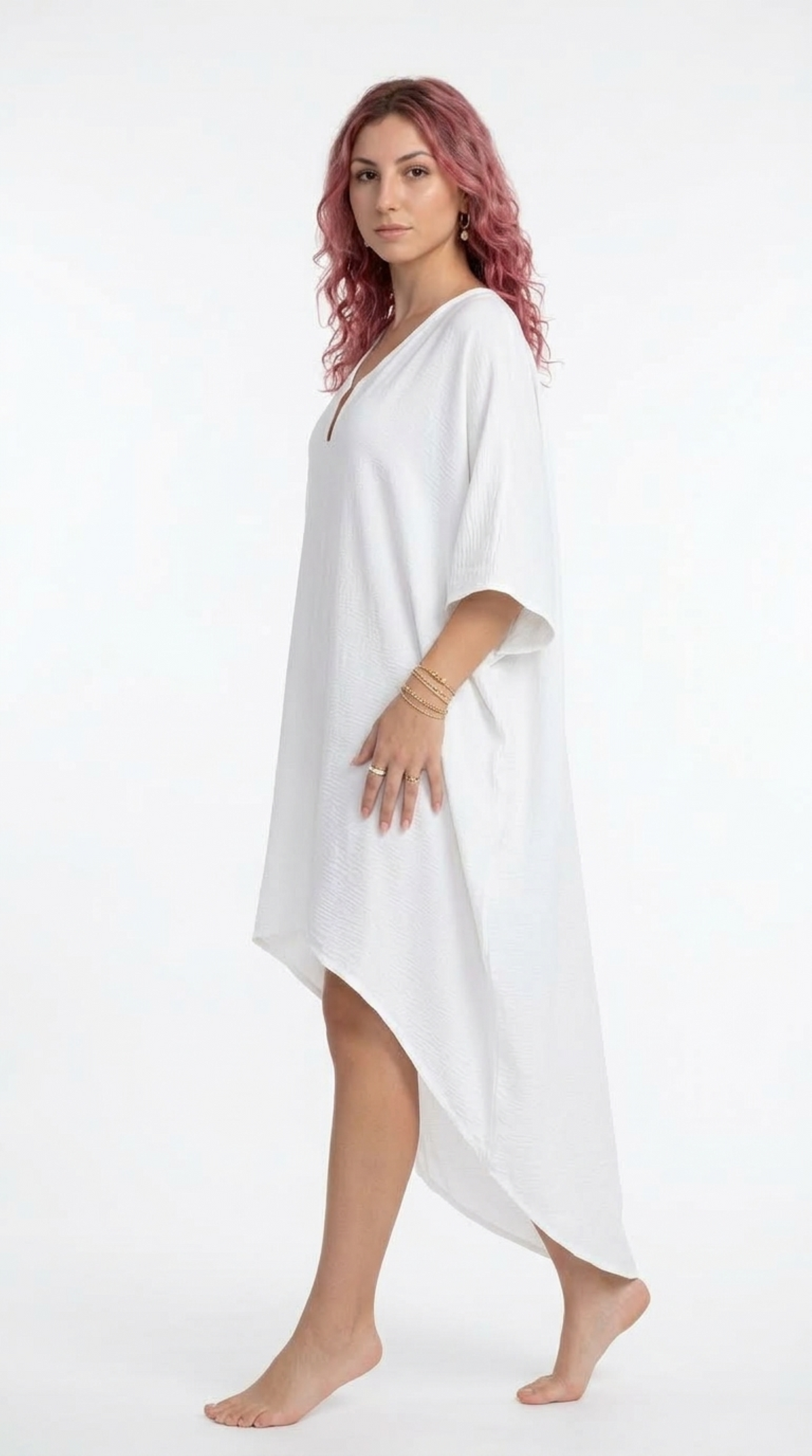 A woman with pink hair wearing a white, loose-fitting kaftan-style cover-up dress, standing against a plain white studio background, from Meleche Fashion or Meléche (short as (Mé)) and shoot taken by Meléche studio photography NYC-USA