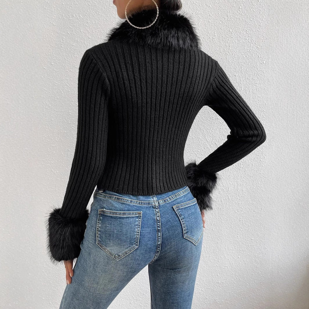 Person wearing a black ribbed sweater with fur cuffs and hem, paired with blue jeans on a white background.