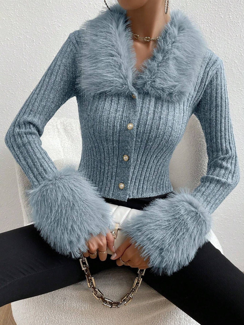 Blue knitted cardigan with fluffy cuffs and collar on a neutral background