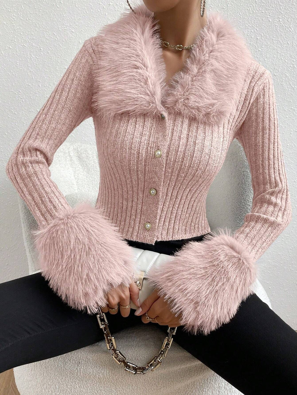 Pink knitted cardigan with fluffy cuffs and collar on a neutral background