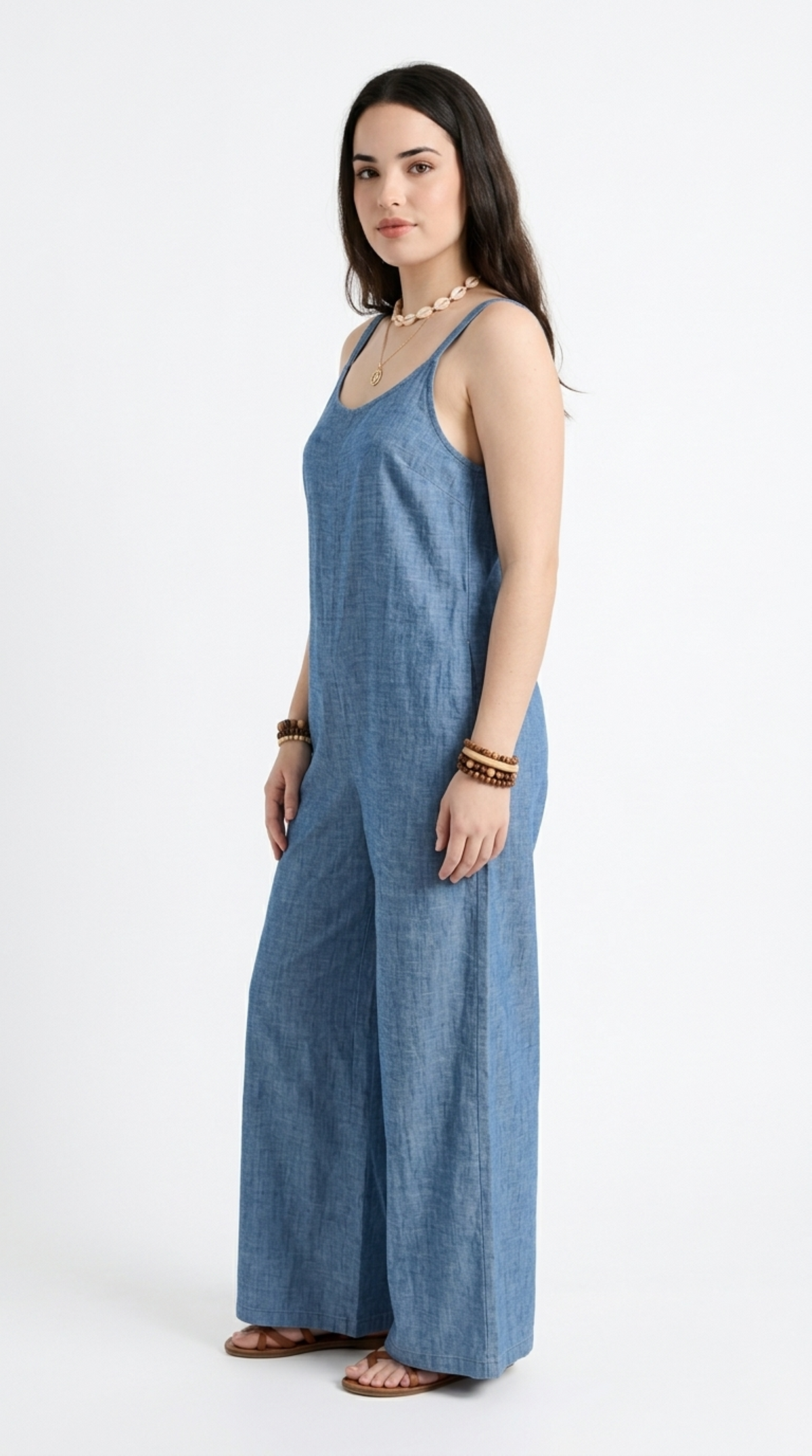 A woman modeling a blue denim wide-leg jumpsuit against a plain white studio background, from Meleche Fashion or Meléche (short as (Mé)) and shoot taken by Meléche studio photography NYC-USA