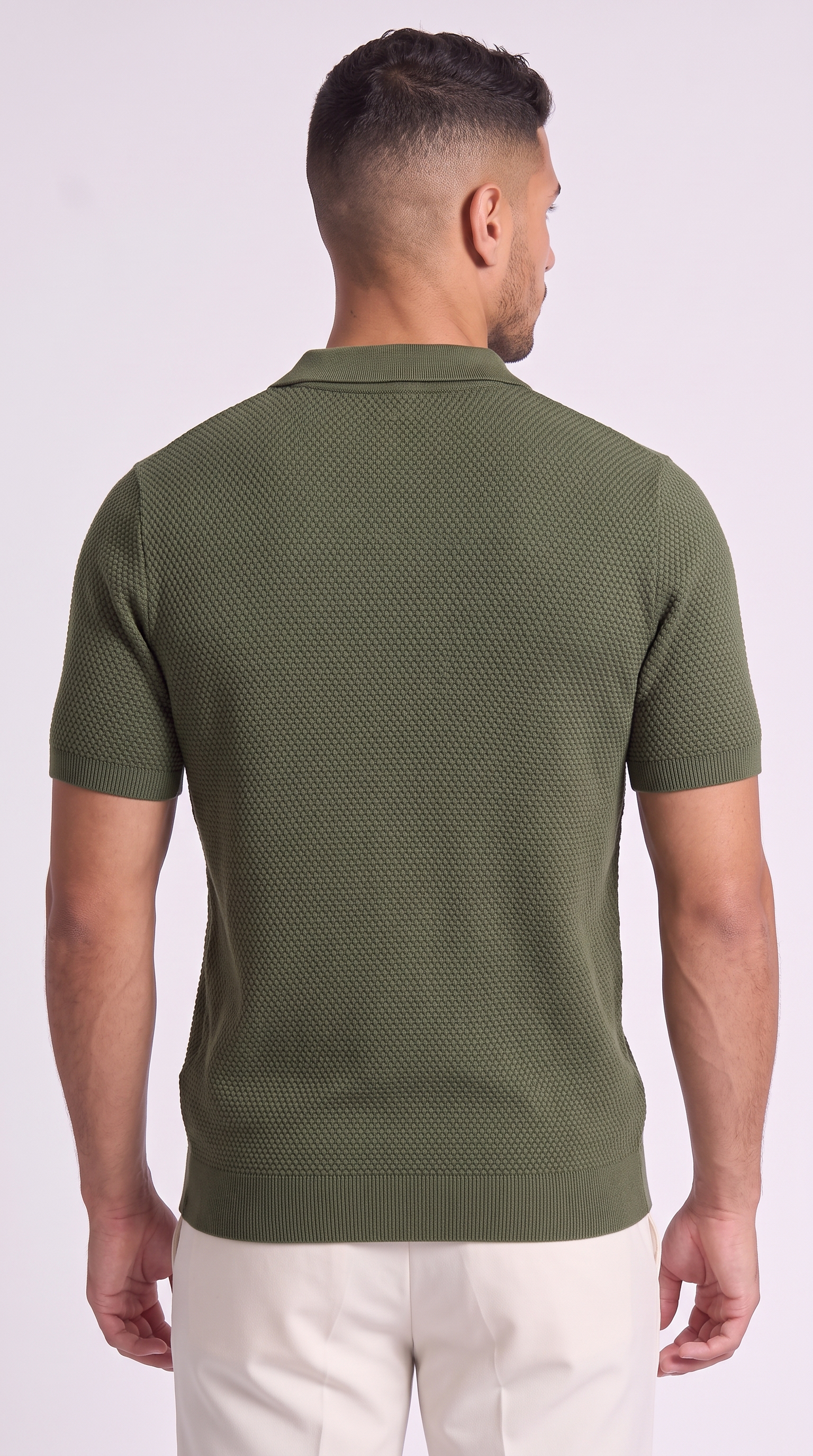 A man viewed from the back wearing a short-sleeve knit polo shirt in olive green, paired with off-white trousers, against a plain light background, from Meleche Fashion USA or Meléche (short as (Mé))