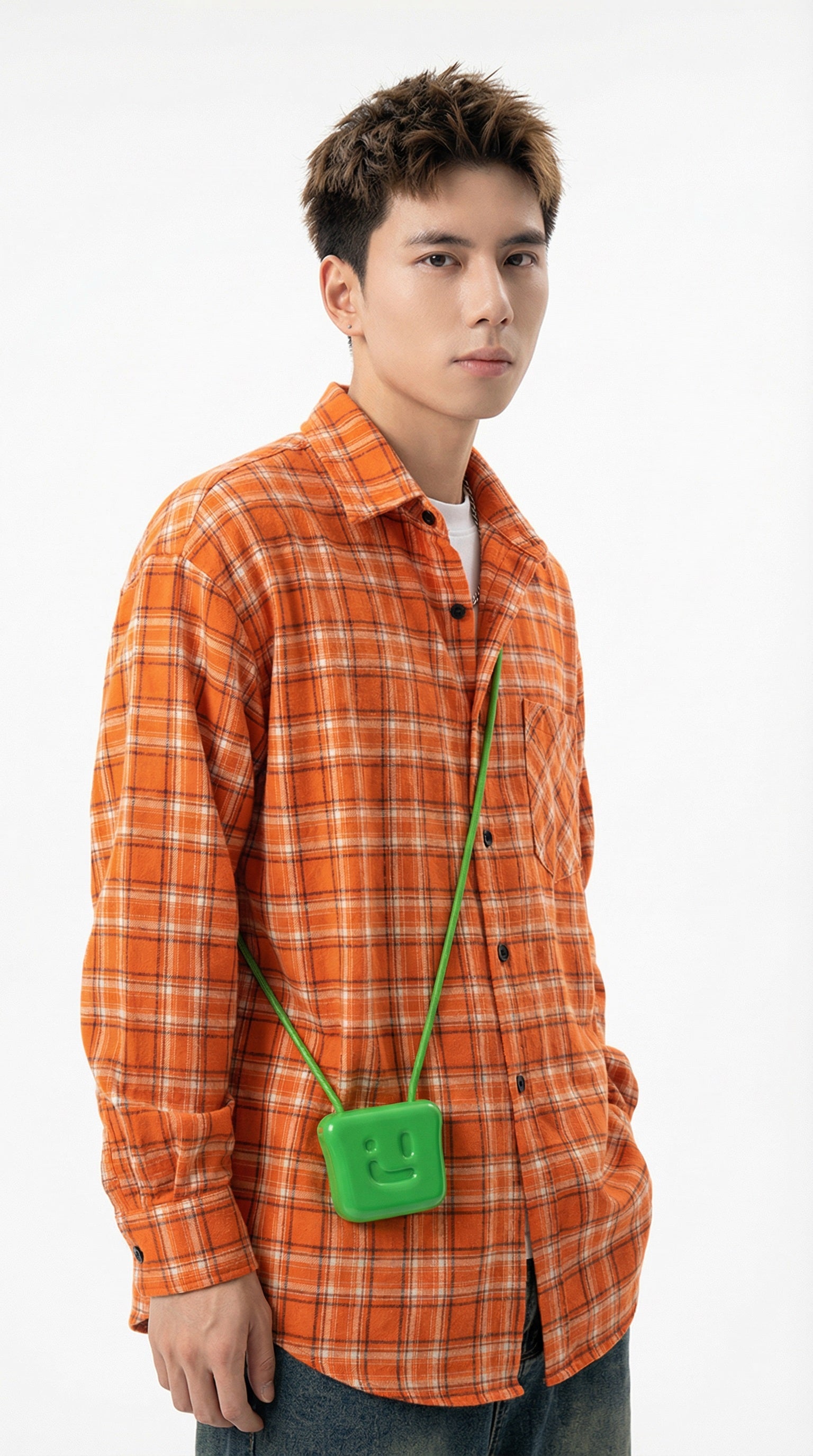 Person wearing an orange plaid shirt and blue jeans standing in a room with framed pictures on the wall.