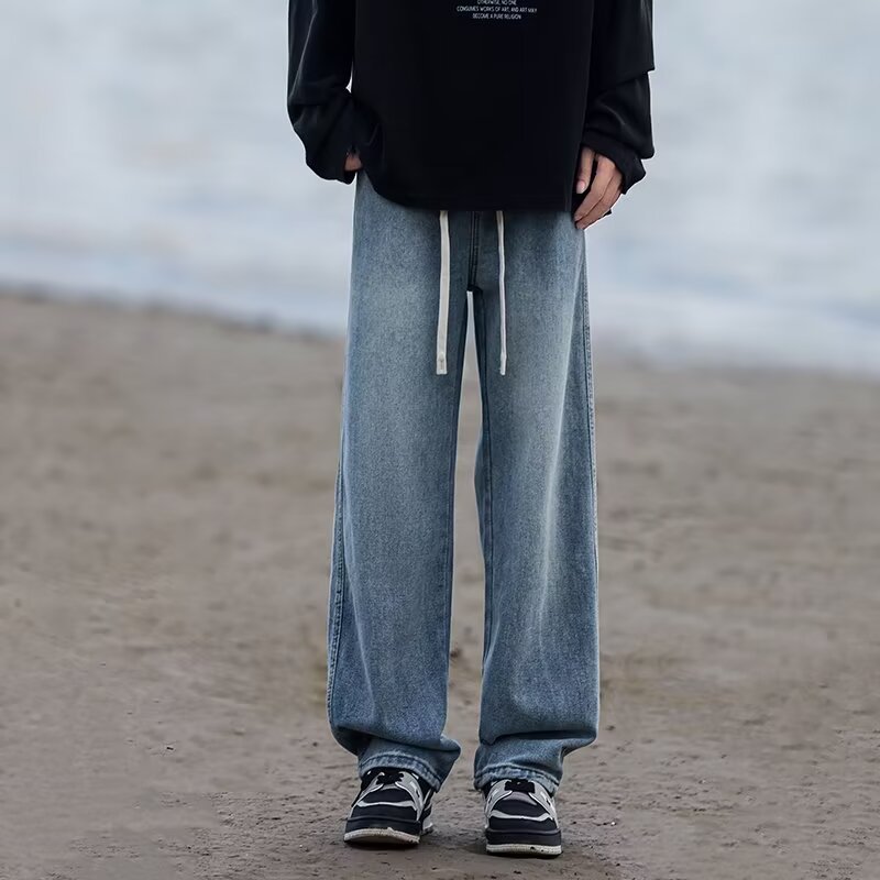 Person wearing blue jeans and black shoes on a beach