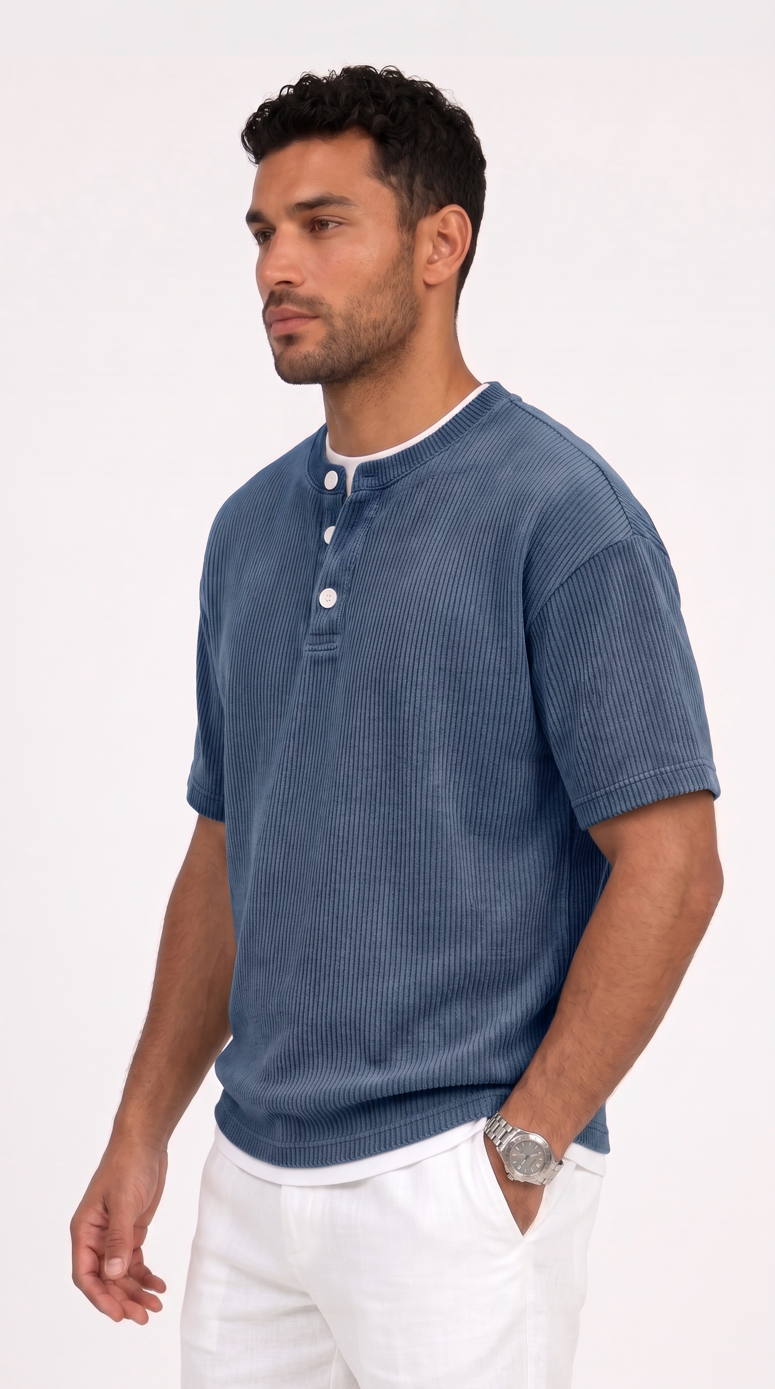 A man wearing a blue short-sleeve henley shirt with white pants, standing against a plain white studio background, from Meleche Fashion USA or Meléche (short as (Mé))