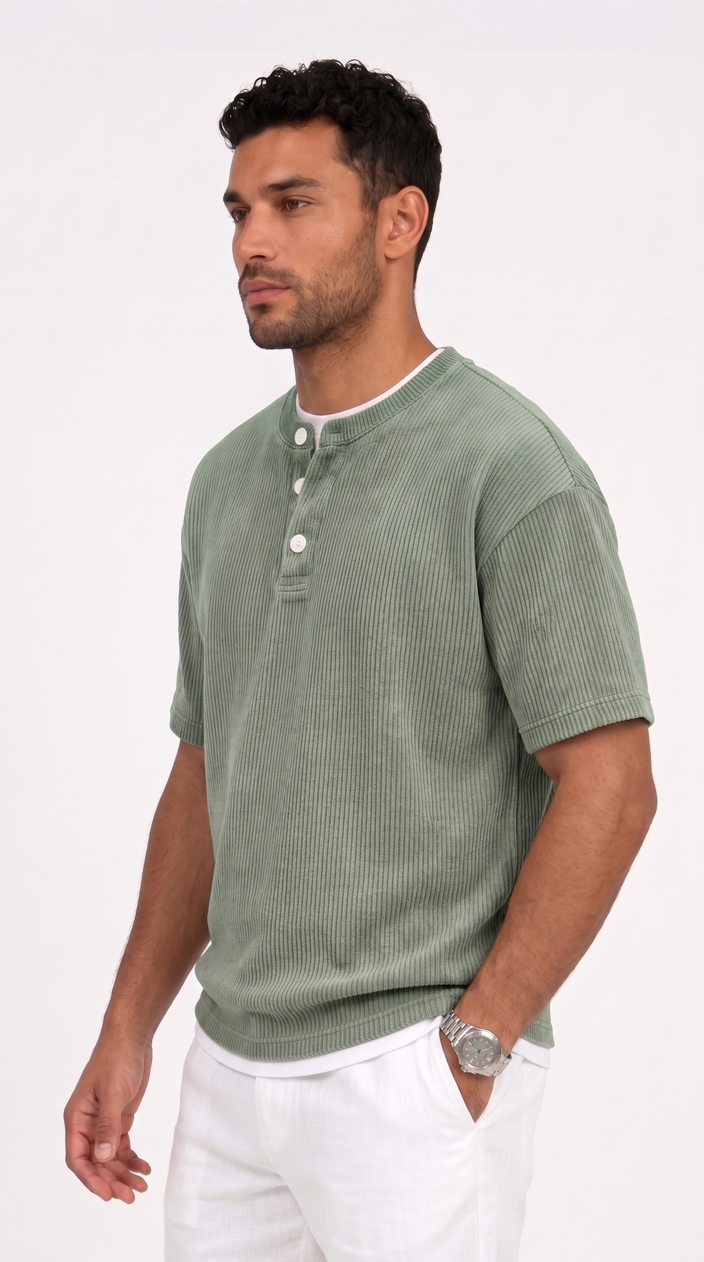 A man wearing a sage green ribbed short-sleeve henley shirt with white buttons and a white undershirt, paired with white pants, photographed against a clean white studio background, from Meleche Fashion USA or Meléche (short as (Mé))