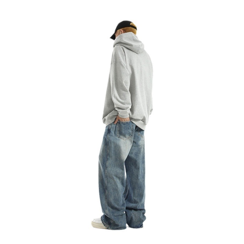 Person wearing a gray hoodie and blue jeans on a white background