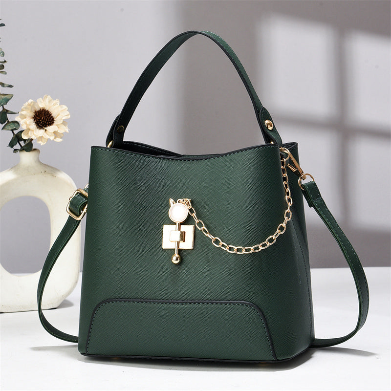 Xen - Green handbag with a gold chain detail on a white surface.