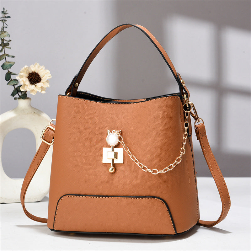Xen - Brown handbag with a decorative chain on a light background