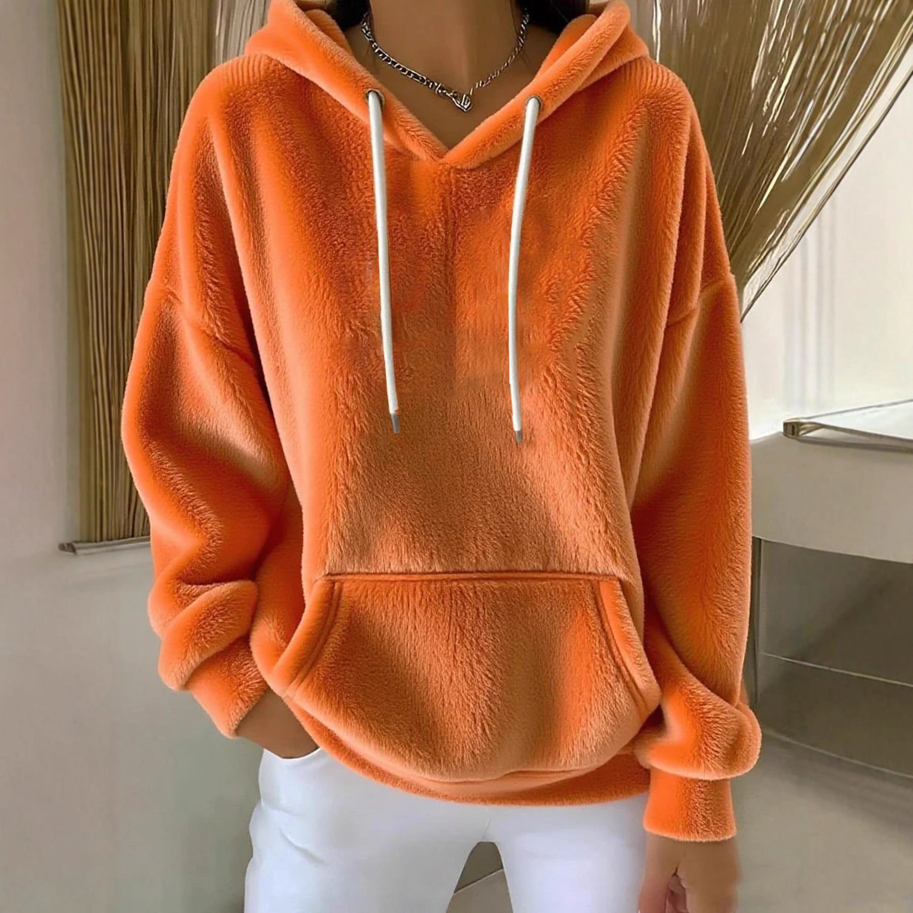 Person wearing an orange textured hoodie with white drawstrings indoors.