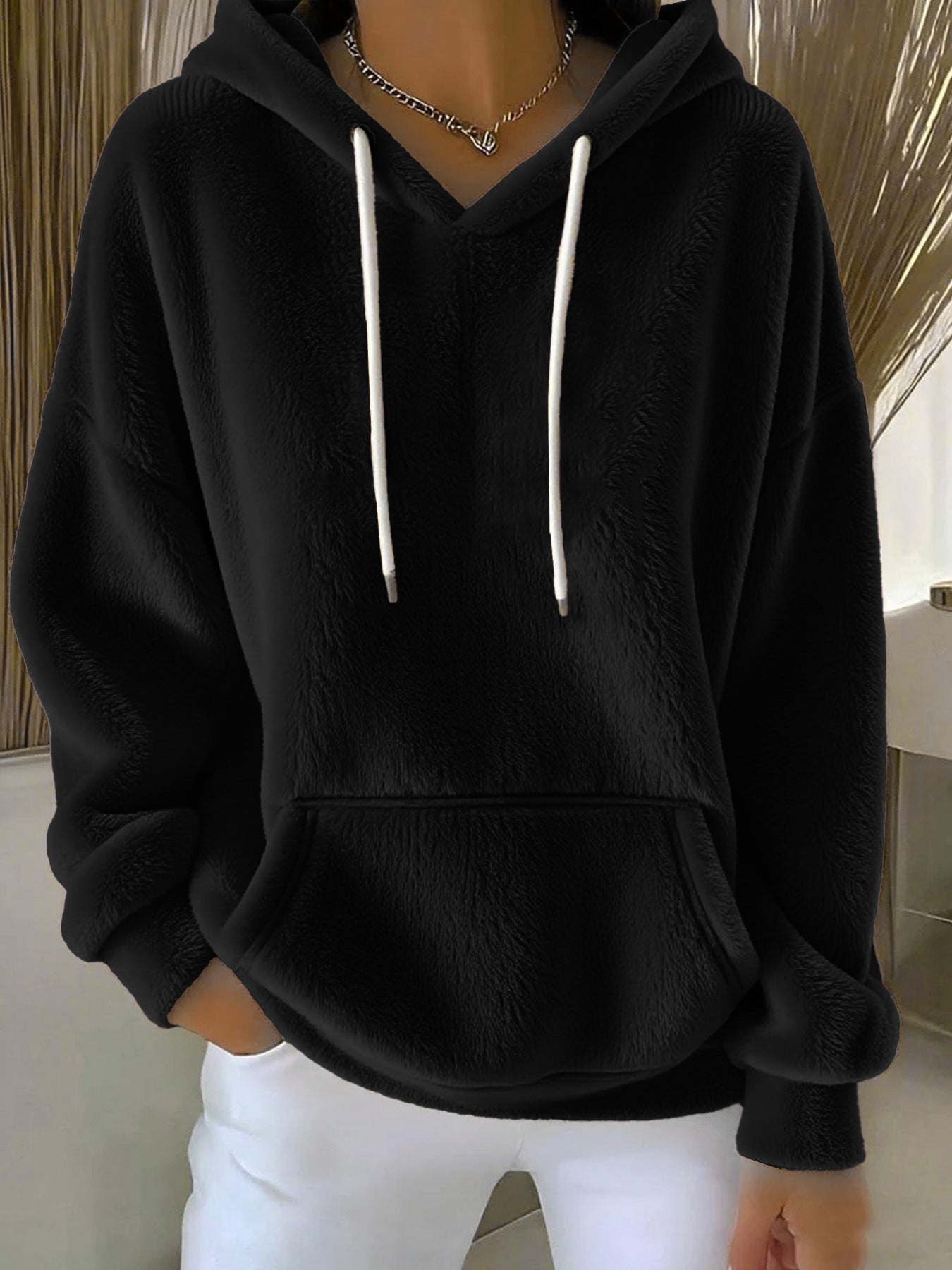 Black hoodie with white drawstrings worn by a person indoors.