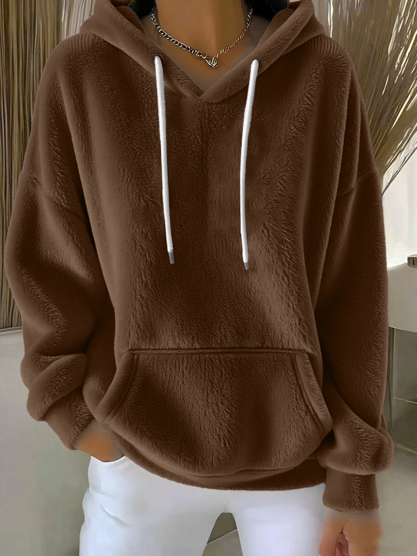 Brown fleece hoodie with white drawstrings worn by a person indoors.