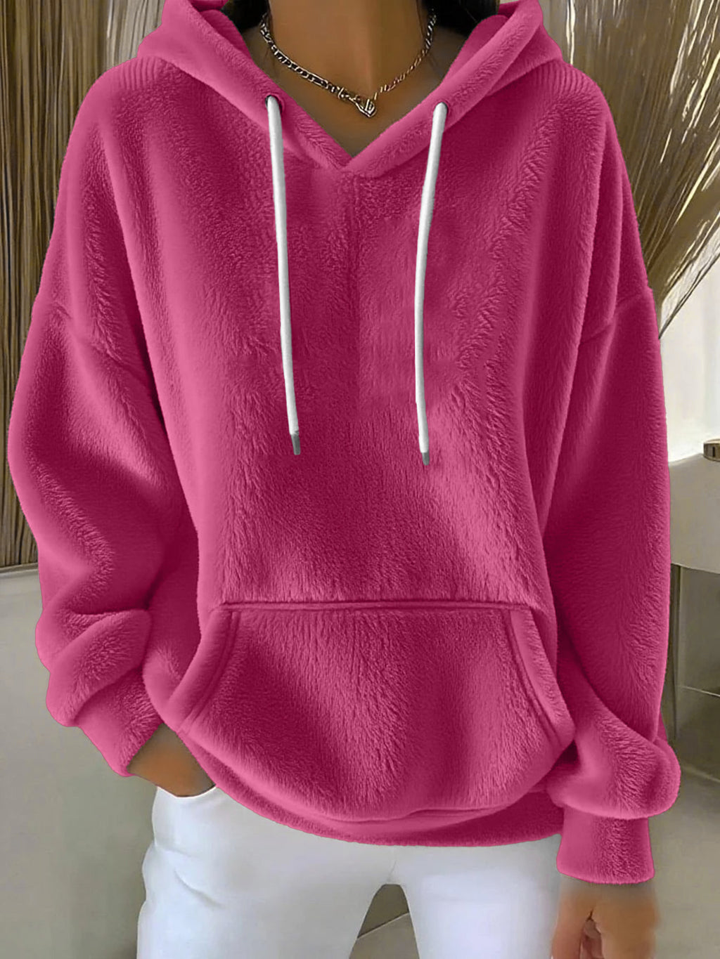 Person wearing a pink hoodie with white drawstrings indoors.