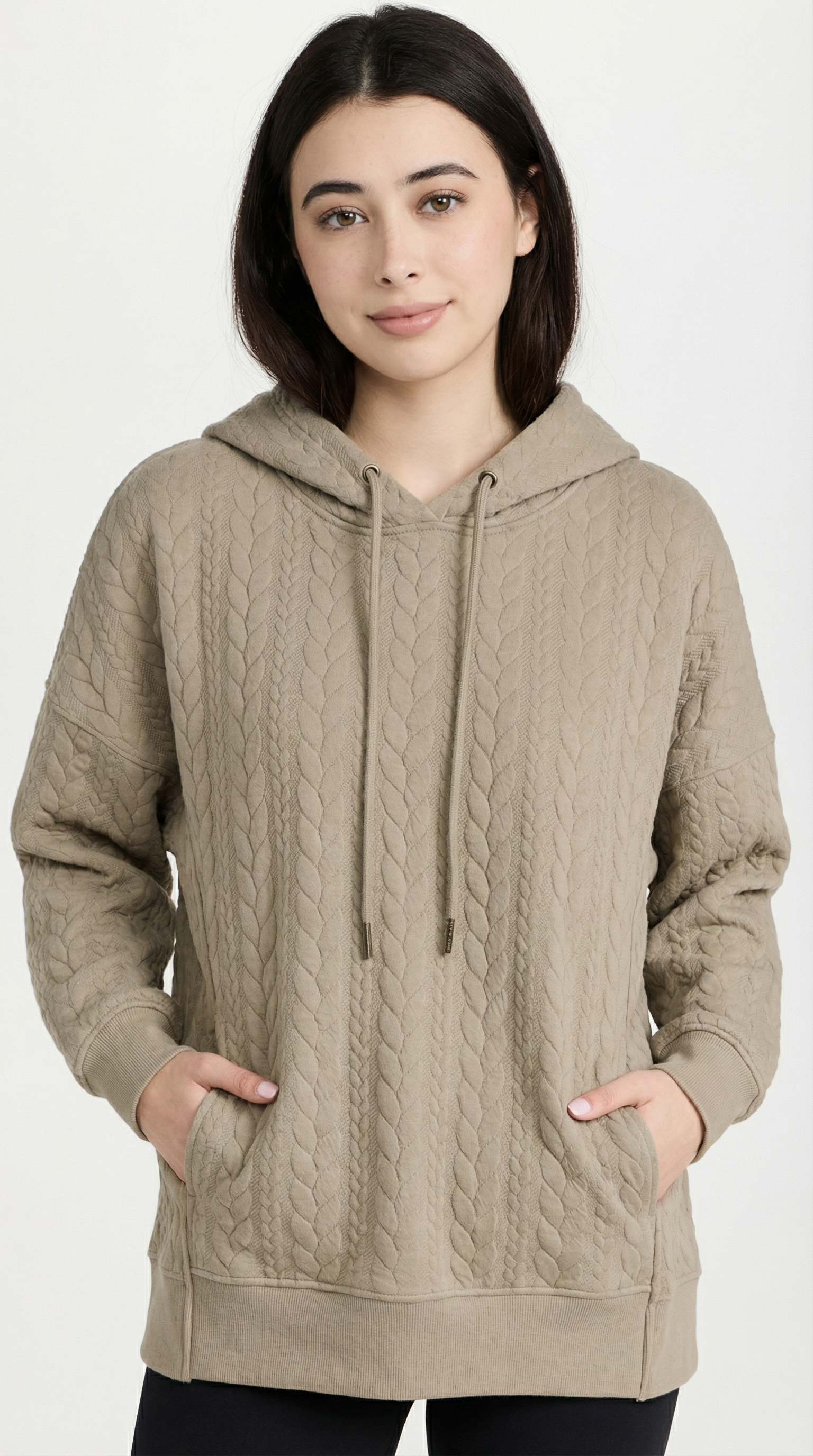 Woman wearing a beige cable knit hoodie on a white background