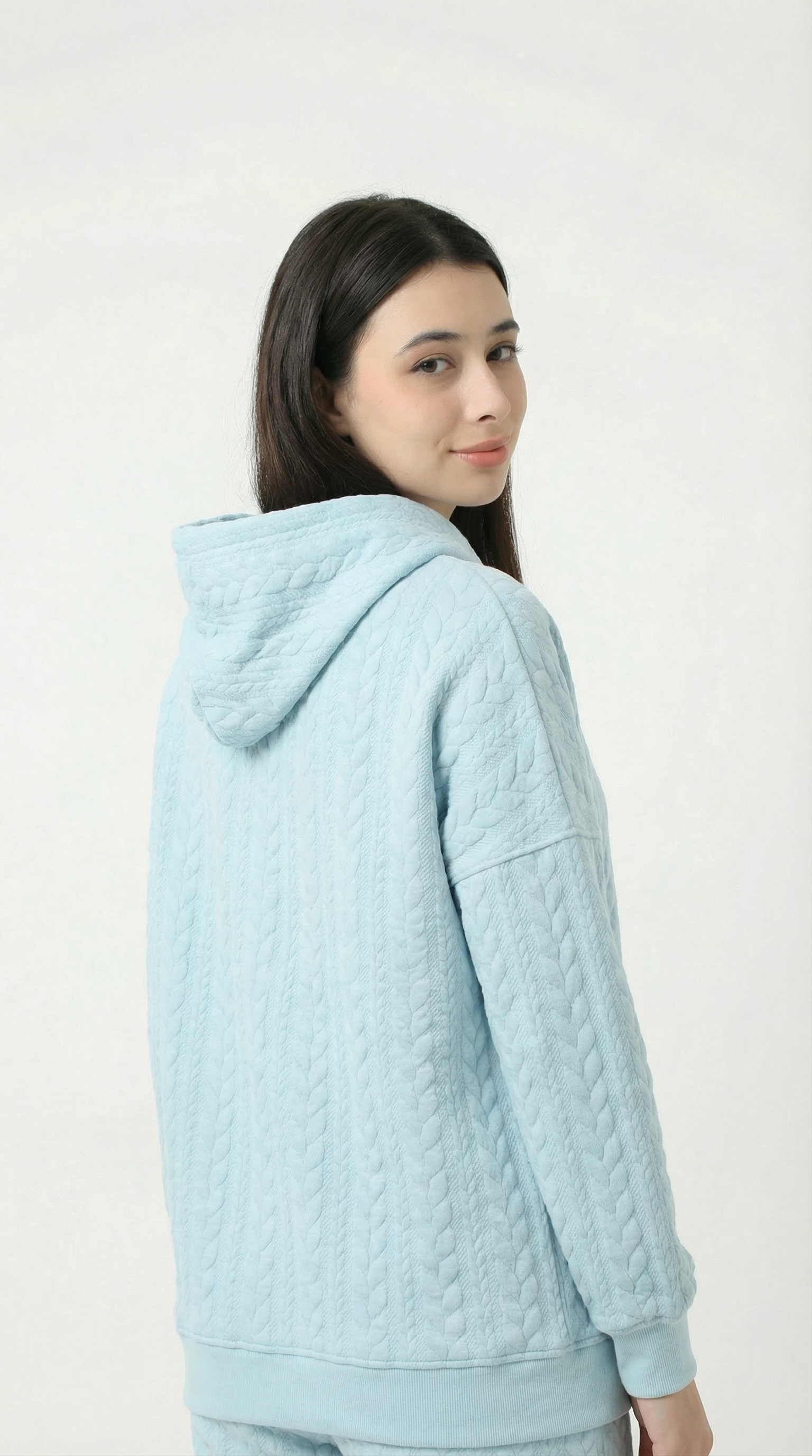 Woman wearing a light blue quilted jacket on a white background