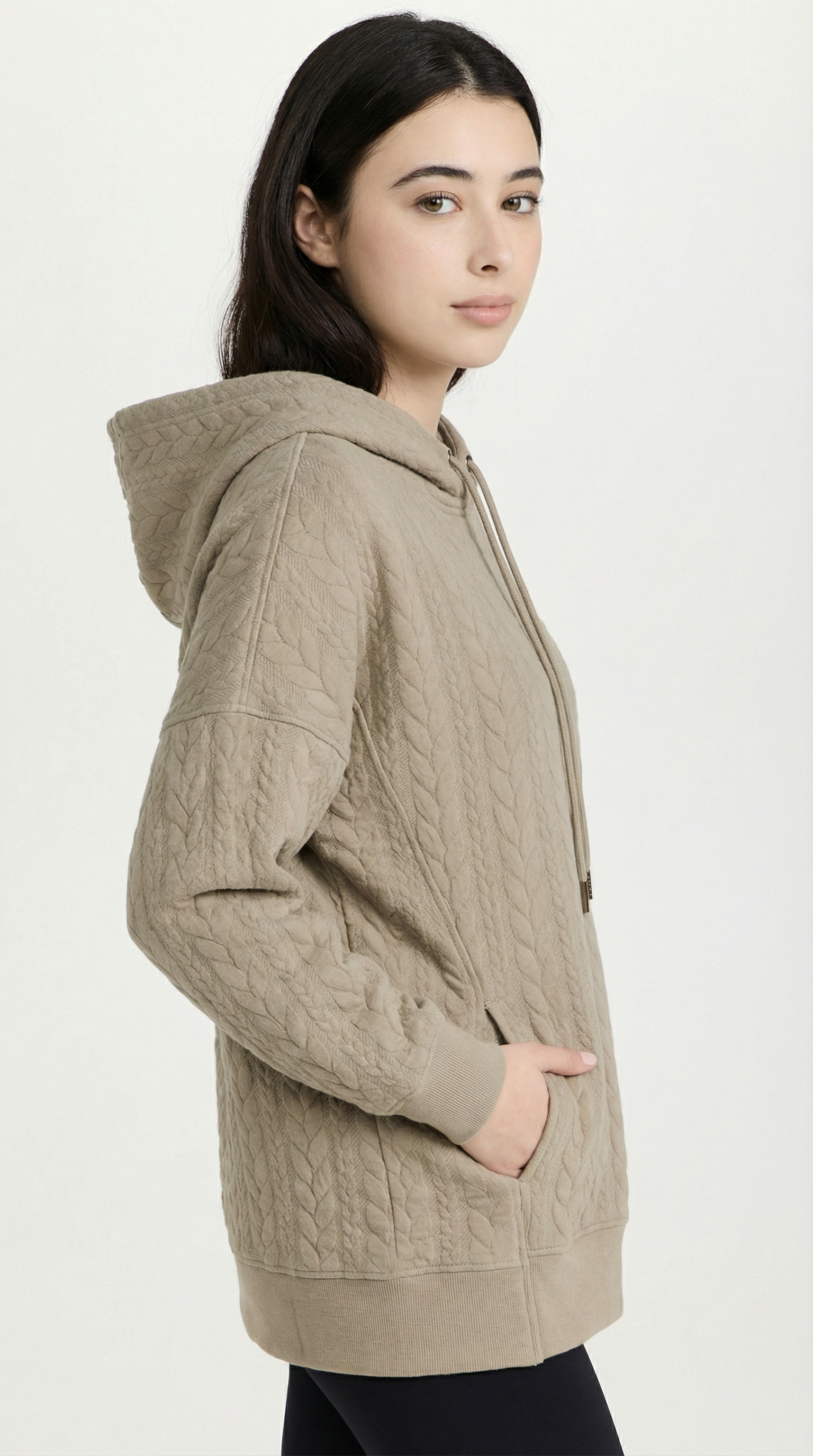 Woman wearing a beige cable knit hoodie on a white background