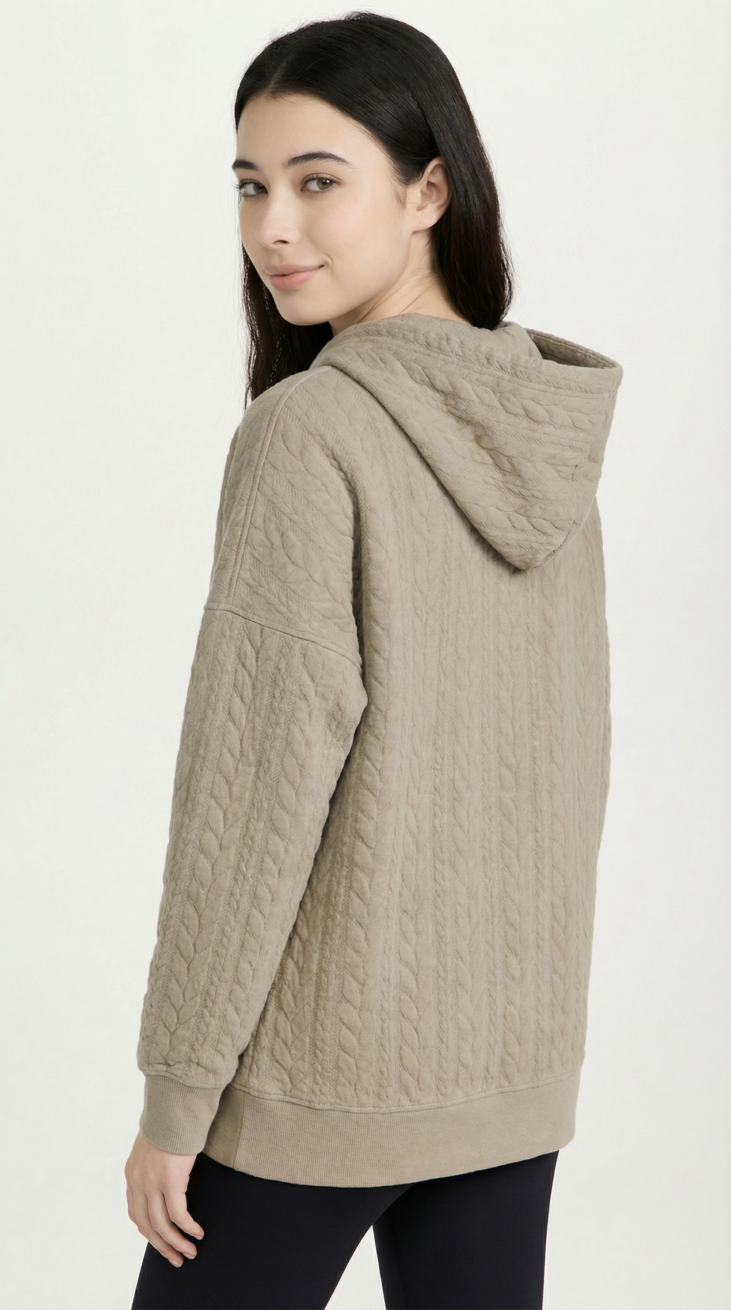 Woman wearing a beige quilted hoodie on a white background