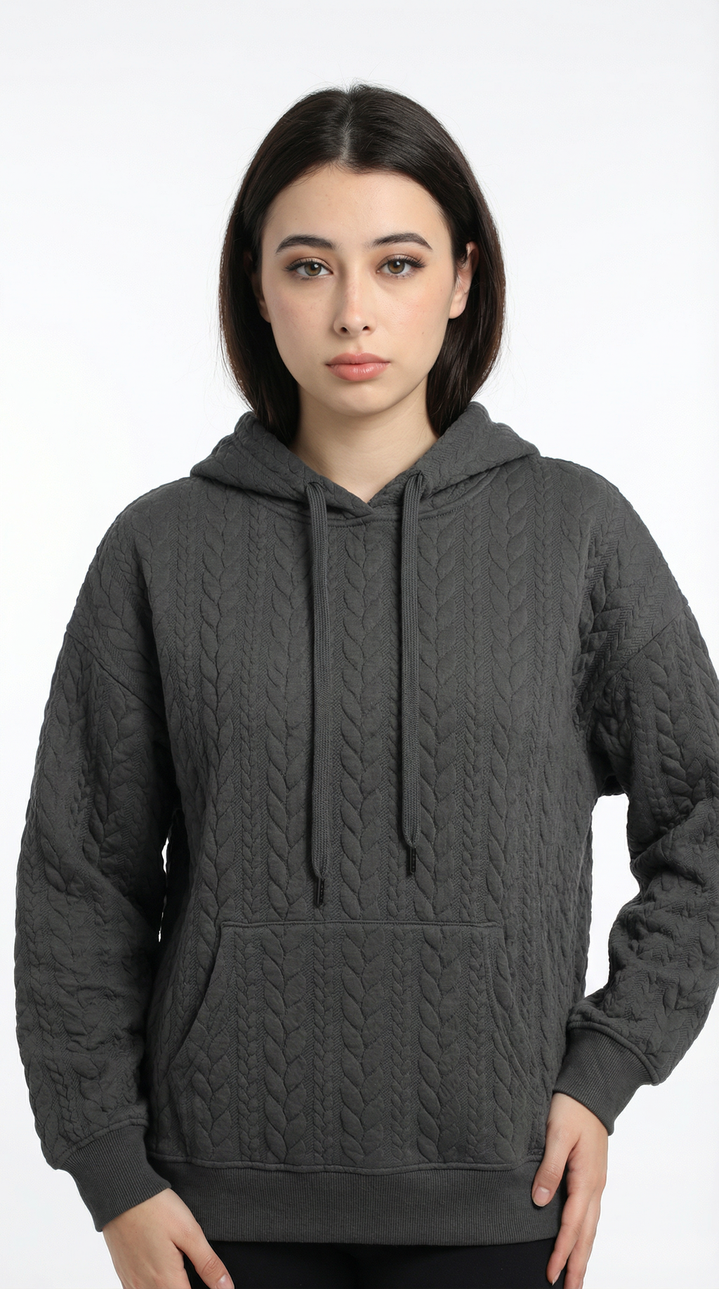 Woman wearing a dark gray cable knit hoodie on a white background