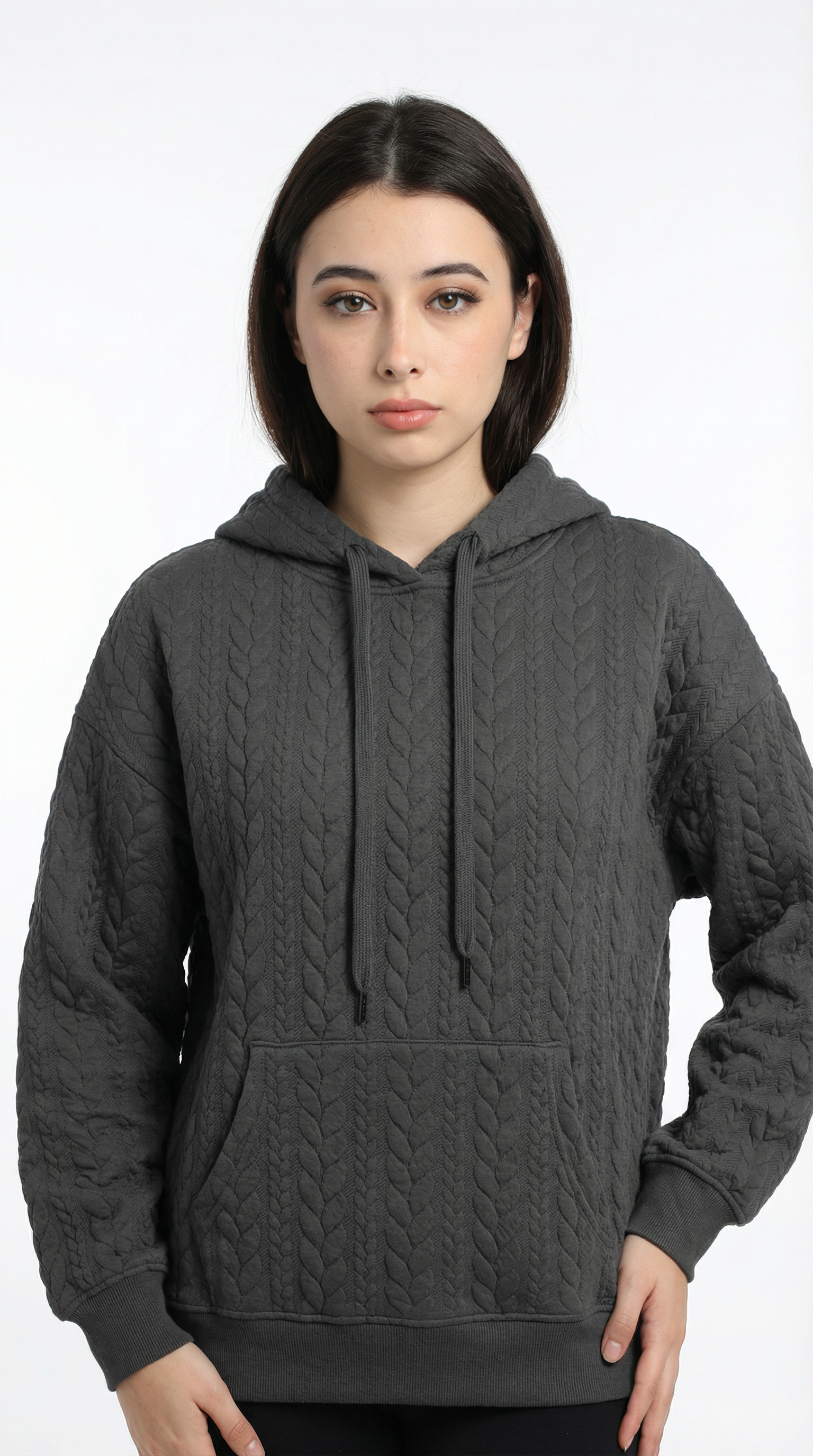 Woman wearing a dark gray cable knit hoodie on a white background