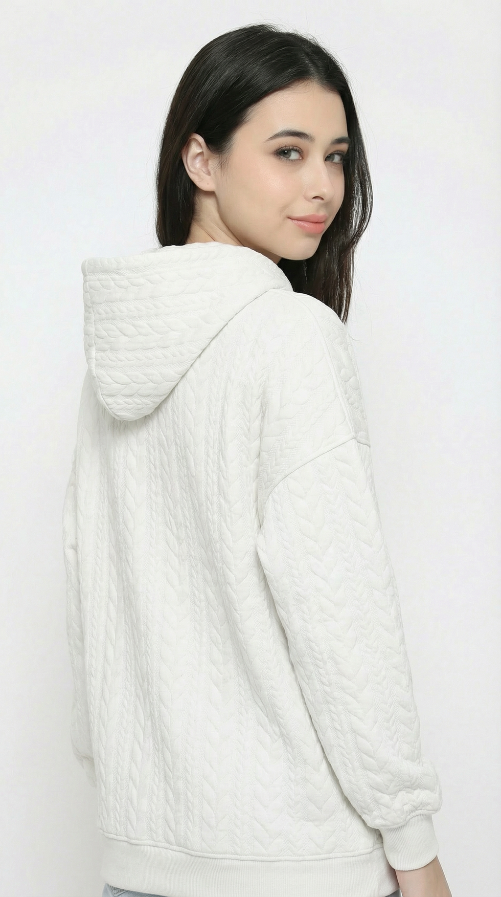 Woman wearing a white textured hoodie on a plain background