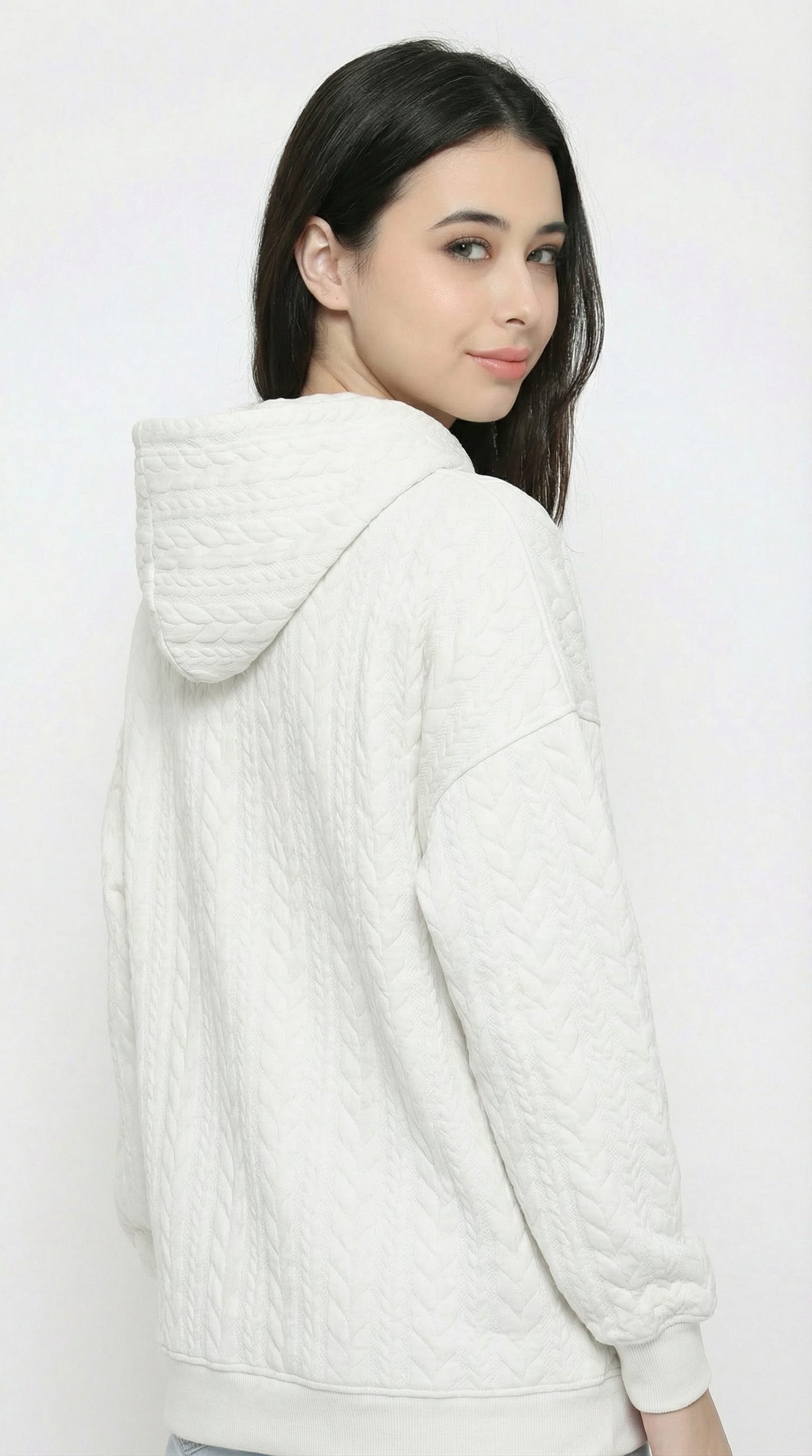 Woman wearing a white textured hoodie on a plain background