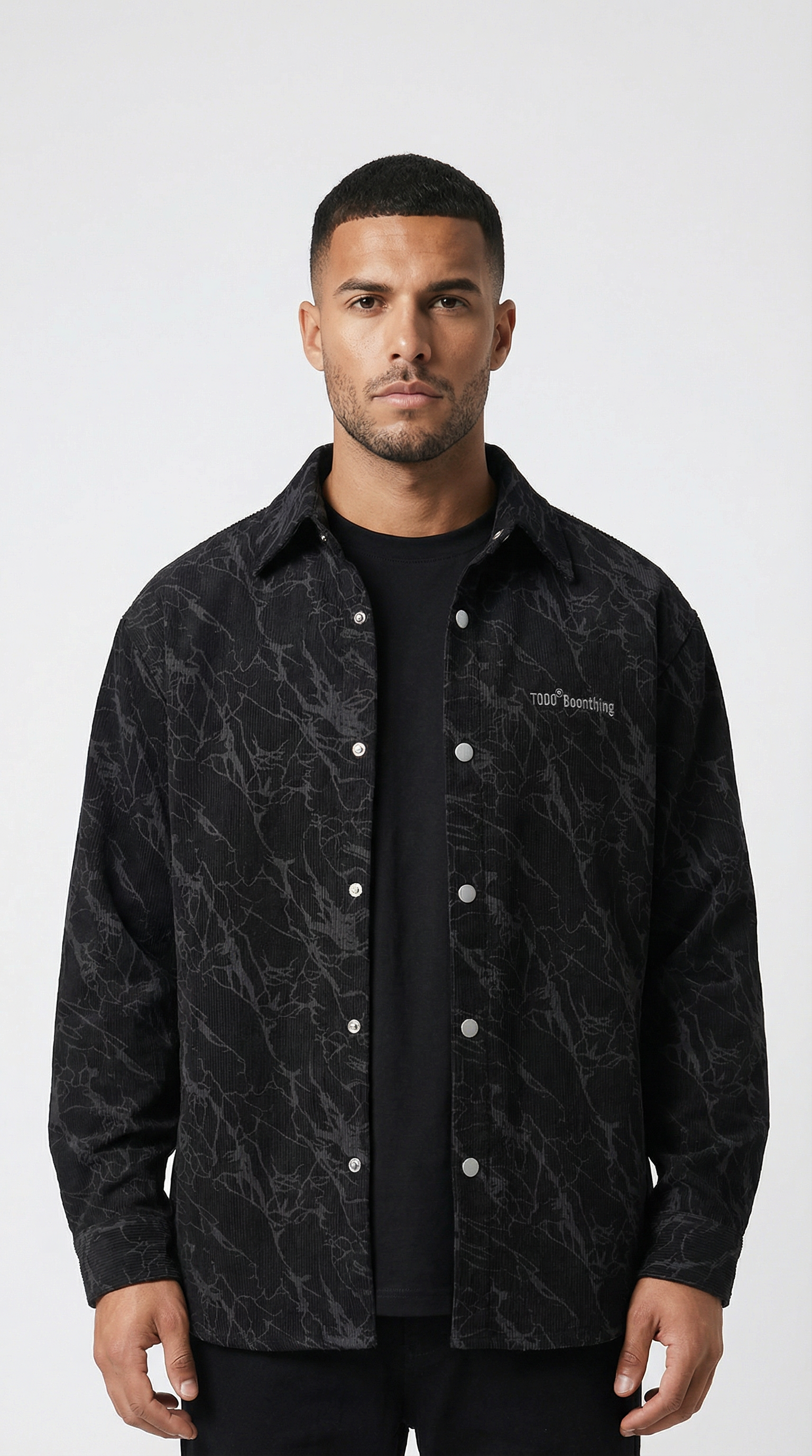 Man wearing a black patterned jacket over a black shirt on a white background