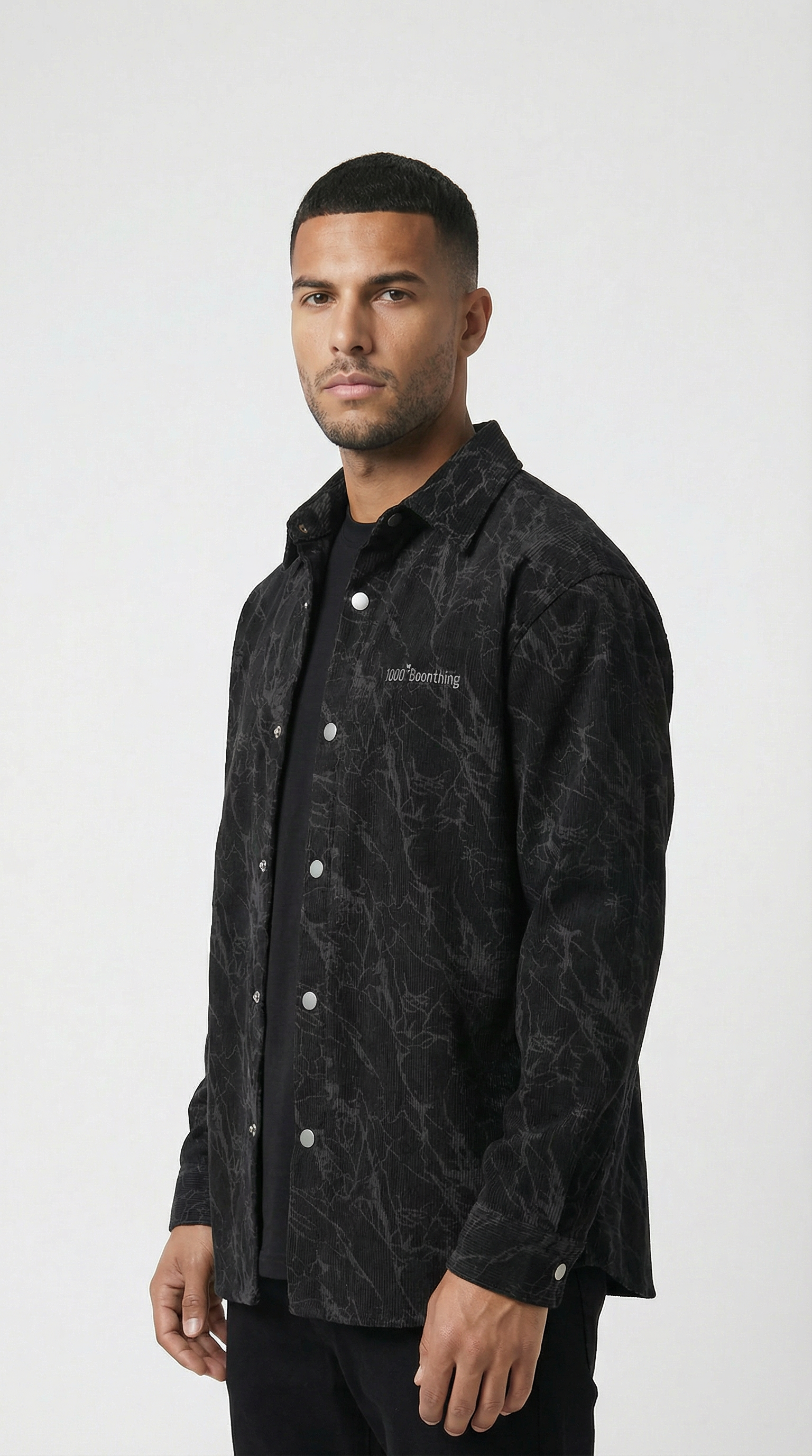 Man wearing a black patterned shirt over a black shirt on a white background