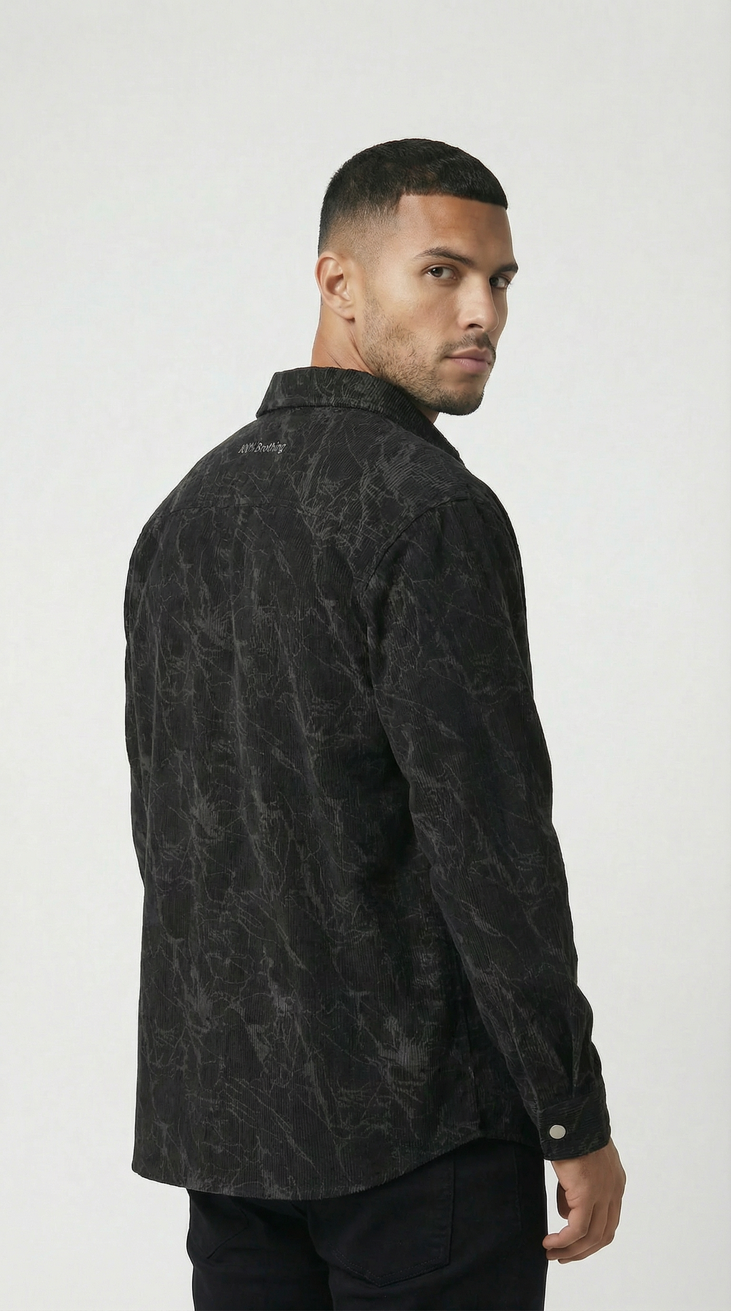 Man wearing a black patterned shirt against a white background