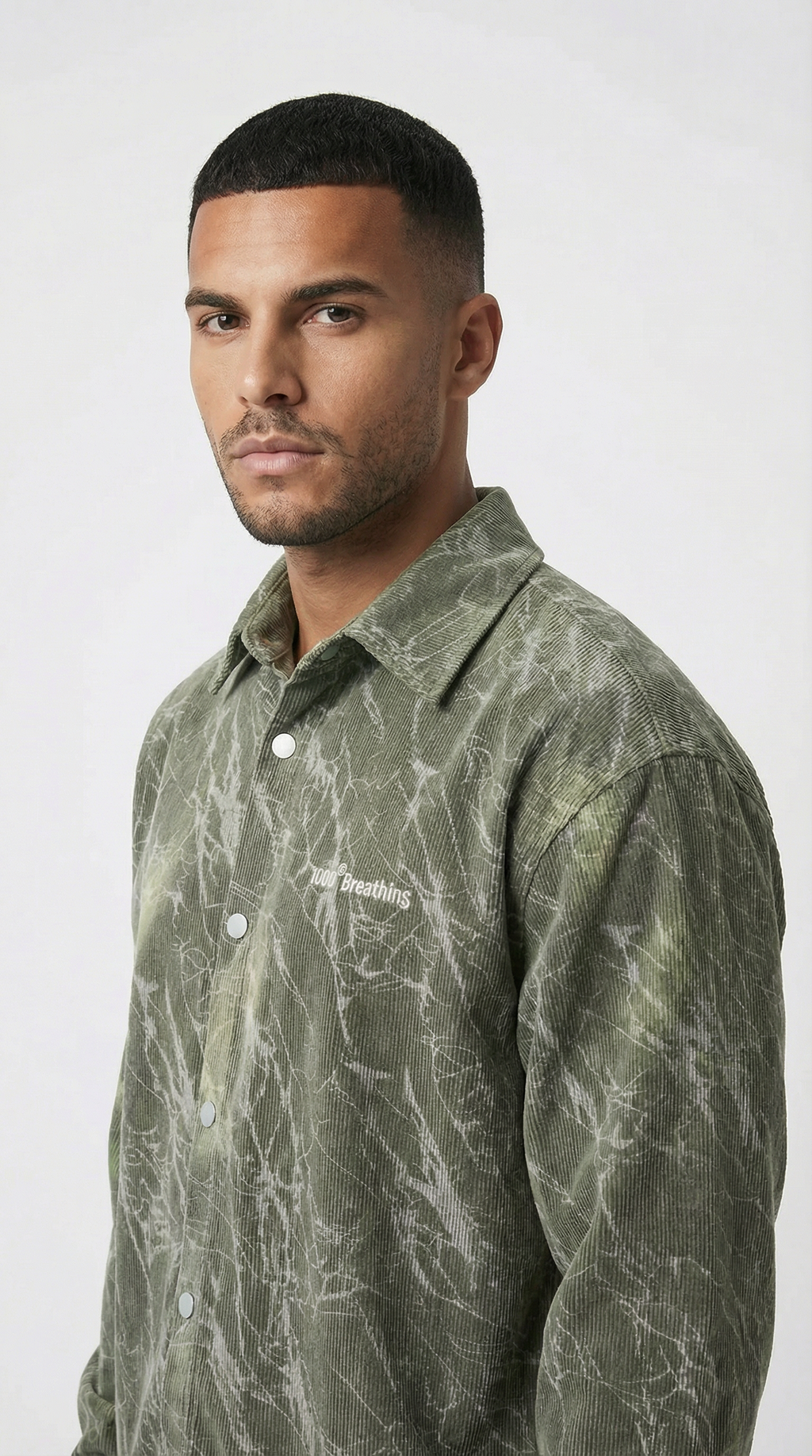 Man wearing a green patterned shirt against a white background