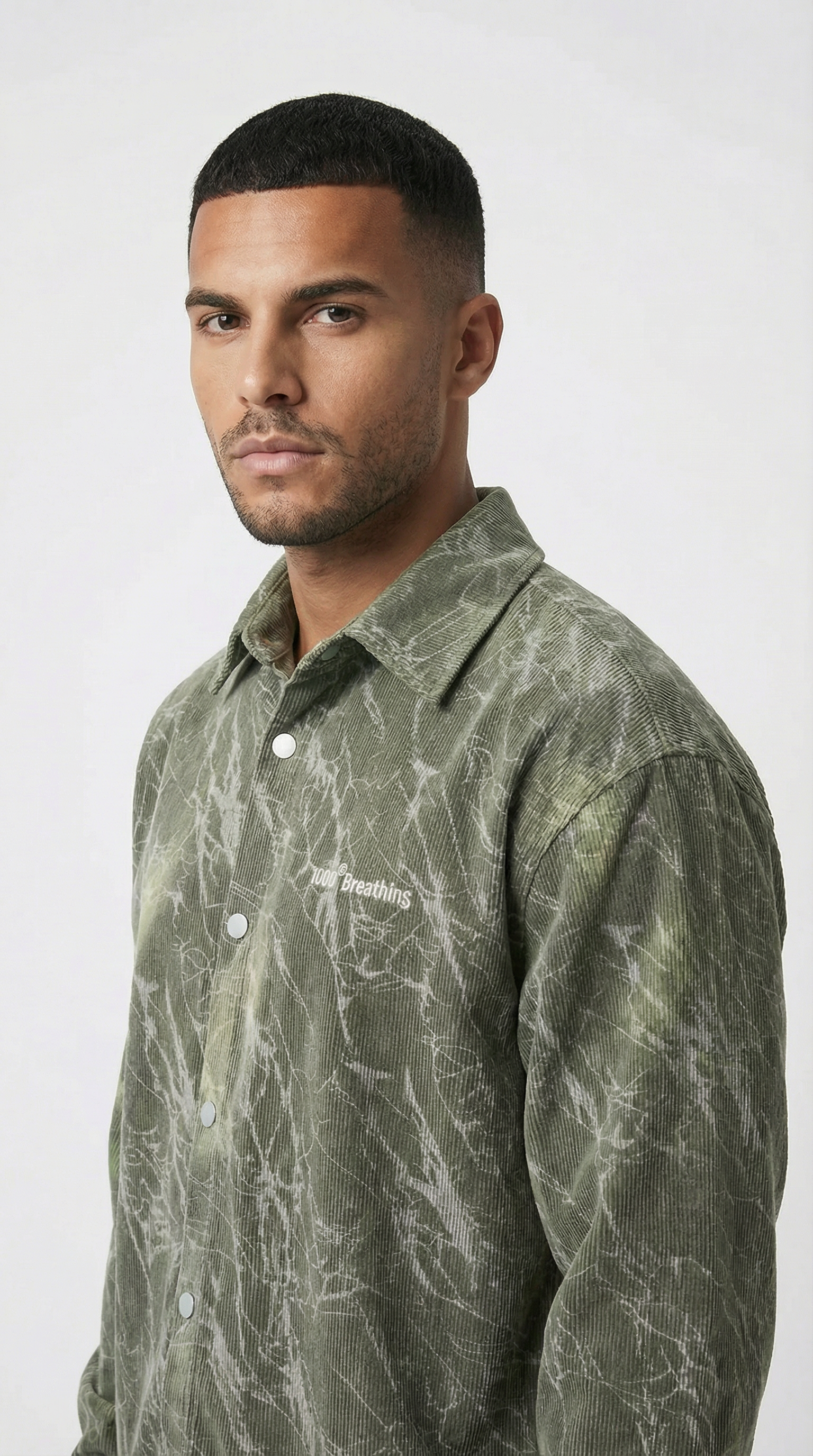 Man wearing a green patterned shirt against a white background