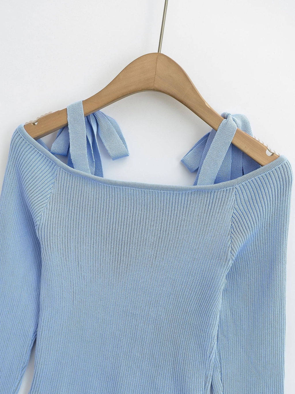 Light blue sweater with bow straps on a wooden hanger from Meleche or Meléche (short as (Mé))