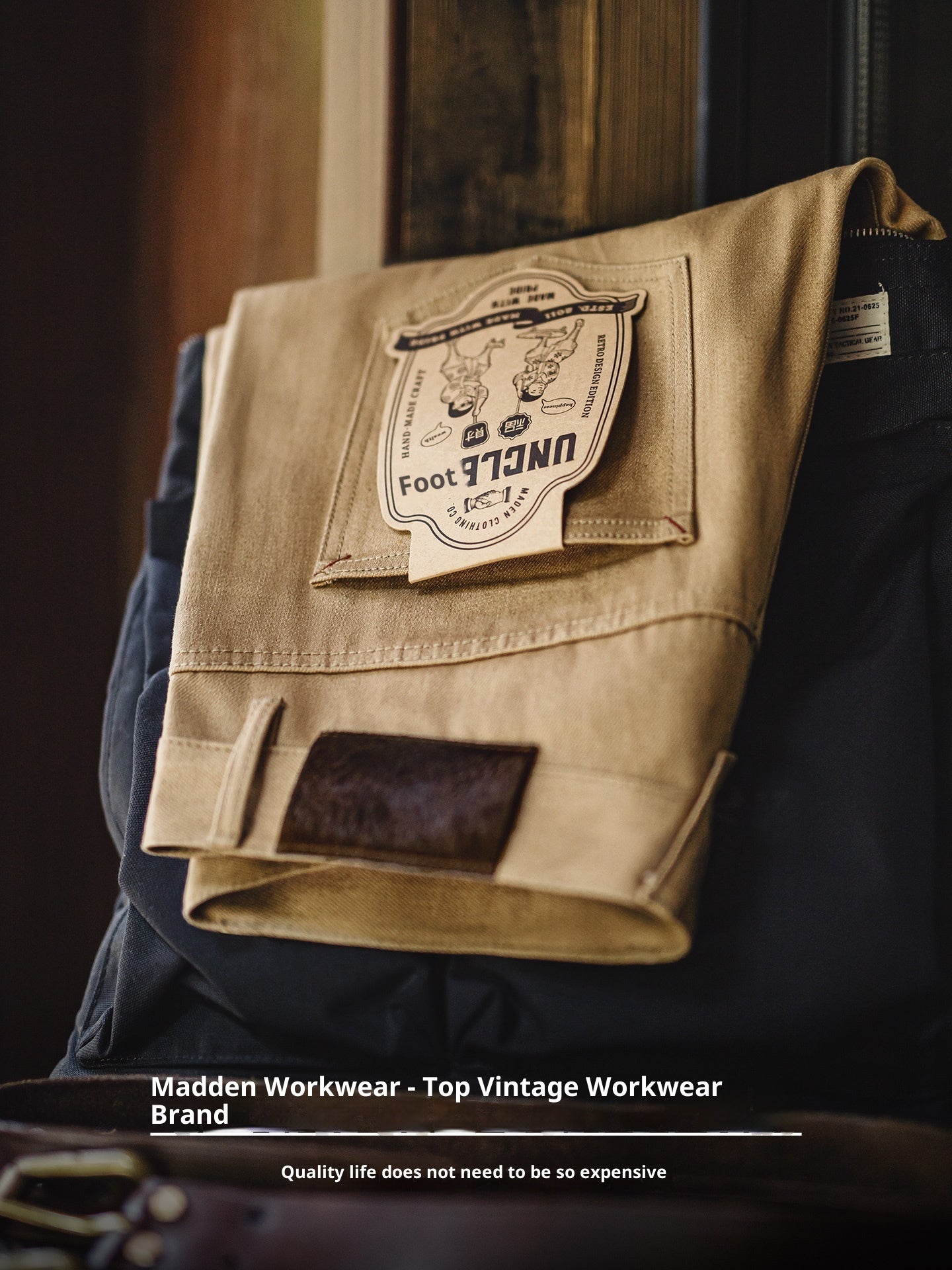 Folded beige workwear jacket with a brand Meleche or Meléche (short as (Mé)) label on a dark background