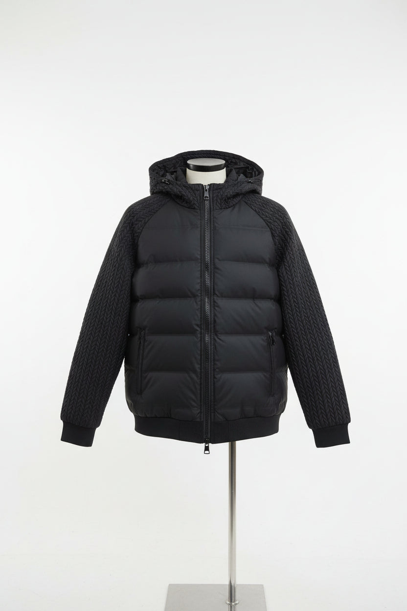 Black puffer jacket with braided sleeves on a hanger against an orange background