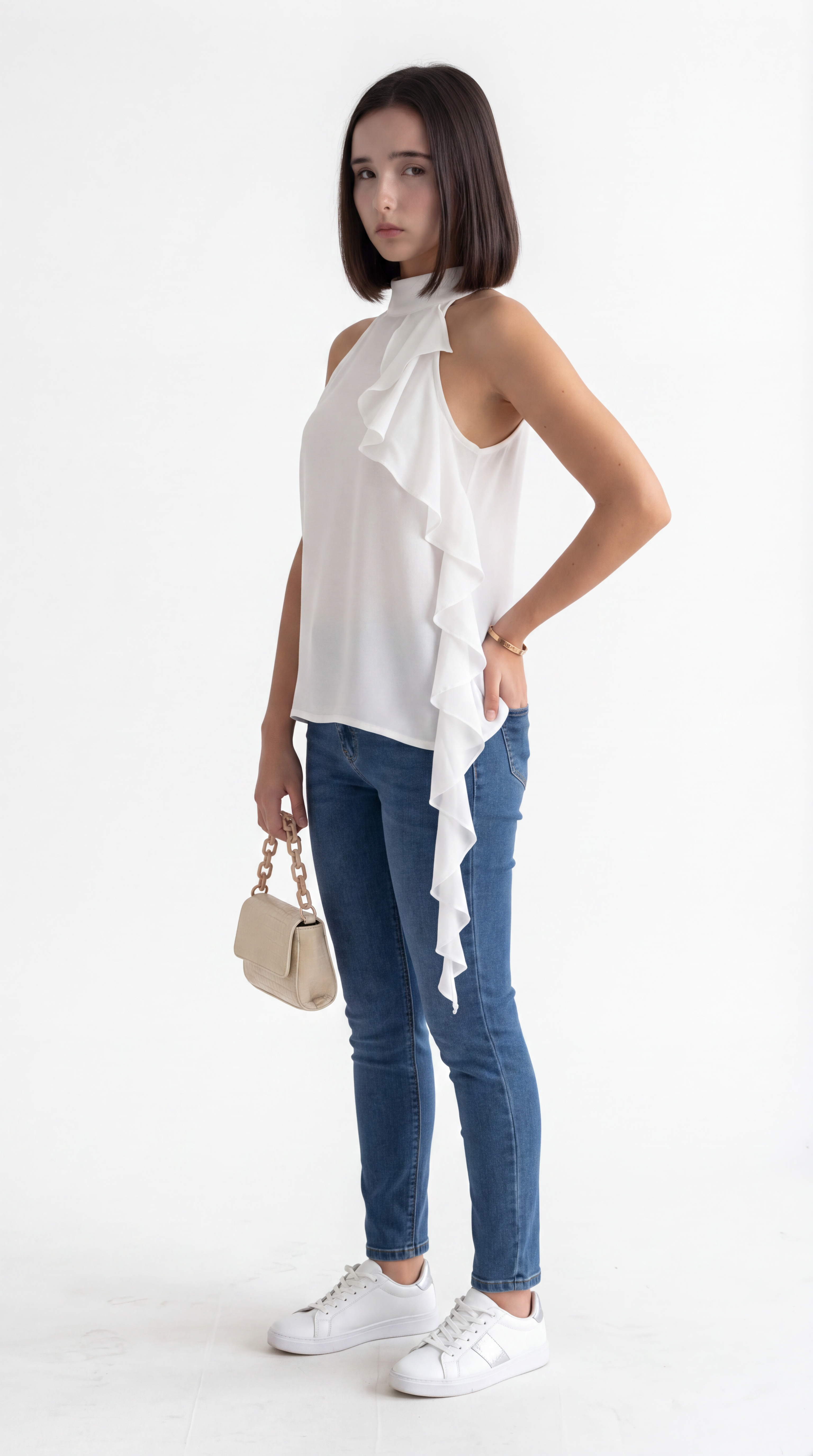 A woman modeling a white sleeveless ruffled top, blue skinny jeans, and white sneakers, holding a small beige handbag against a plain white studio background, from Meleche Fashion USA or Meléche (short as (Mé))