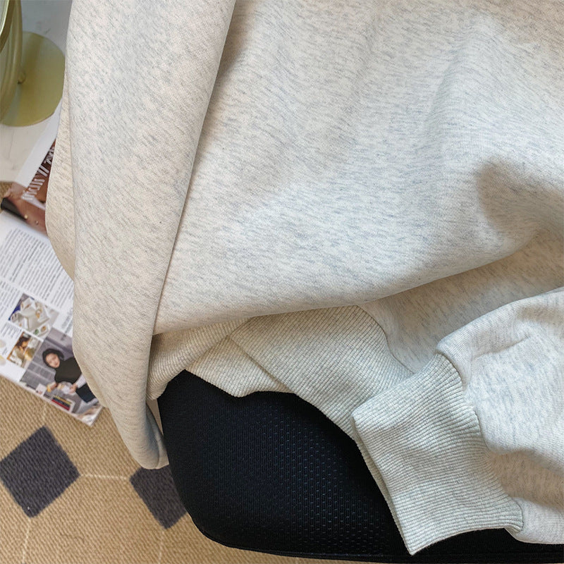 Close-up of a light gray sweater with a textured pattern on a surface.