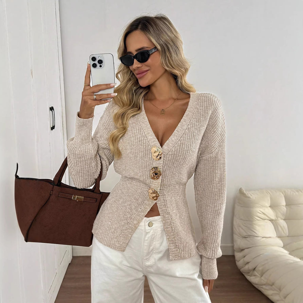 Woman taking a mirror selfie wearing a beige cardigan and white pants, holding a brown handbag.